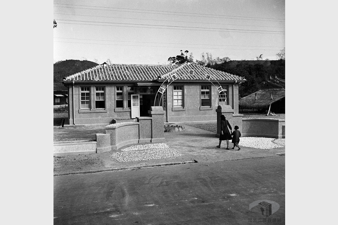 民國41年(1952)，一位母親正牽著小孩走進新埔衛生所；1950年代，對於國民健康的提升與概念的建立，各鄉鎮衛生所扮演了很重要的角色。檔案影像來源：國家發展委員會檔案管理局,檔案支援教學網(https://art.archives.gov.tw/FileImg.aspx?FileID=2823&ImgID=9669)