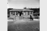 民國41年(1952)，一位母親正牽著小孩走進新埔衛生所；1950年代，對於國民健康的提升與概念的建立，各鄉鎮衛生所扮演了很重要的角色。檔案影像來源：國家發展委員會檔案管理局,檔案支援教學網(https://art.archives.gov.tw/FileImg.aspx?FileID=2823&ImgID=9669)